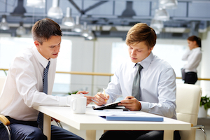 Ung businessmand får hjælp til at blive bedre til at uddelegere sine opgaver til andre kollegaer for at blive mere produktiv og effektiv