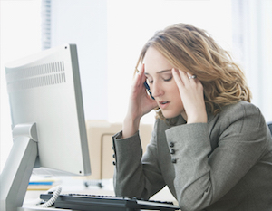 Stressramt kvinde sidder og stirrer ind i computerskærmen og kan ikke overskue alle de arbejdsopgaver som er givet til hende